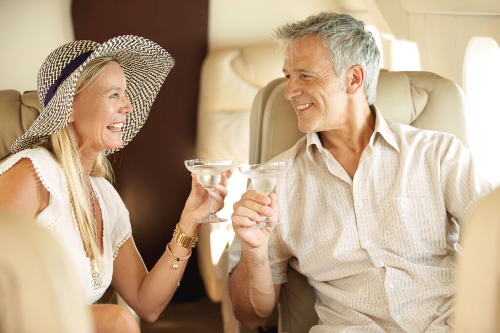 Bonding,On,A,Romantic,Getaway.,Smiling,And,Happy,Couple,Seated Ehepaar stößt im Flugzeug bei einer Fly In Safari an